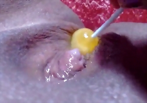 Sweet girl shoves a yellow candy in her little pussy